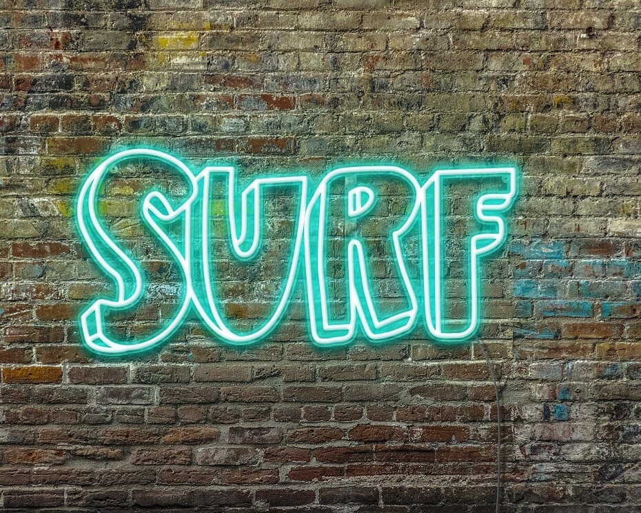 A personalized neon sign of the word 'surf' on a brick wall